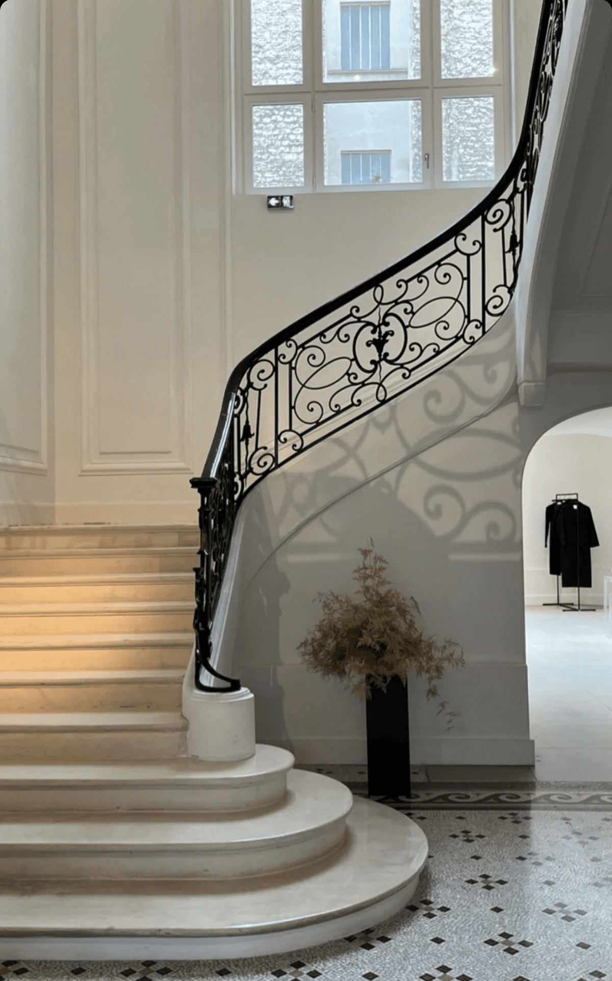 An elegant curved staircase with black ironwork and warm stone